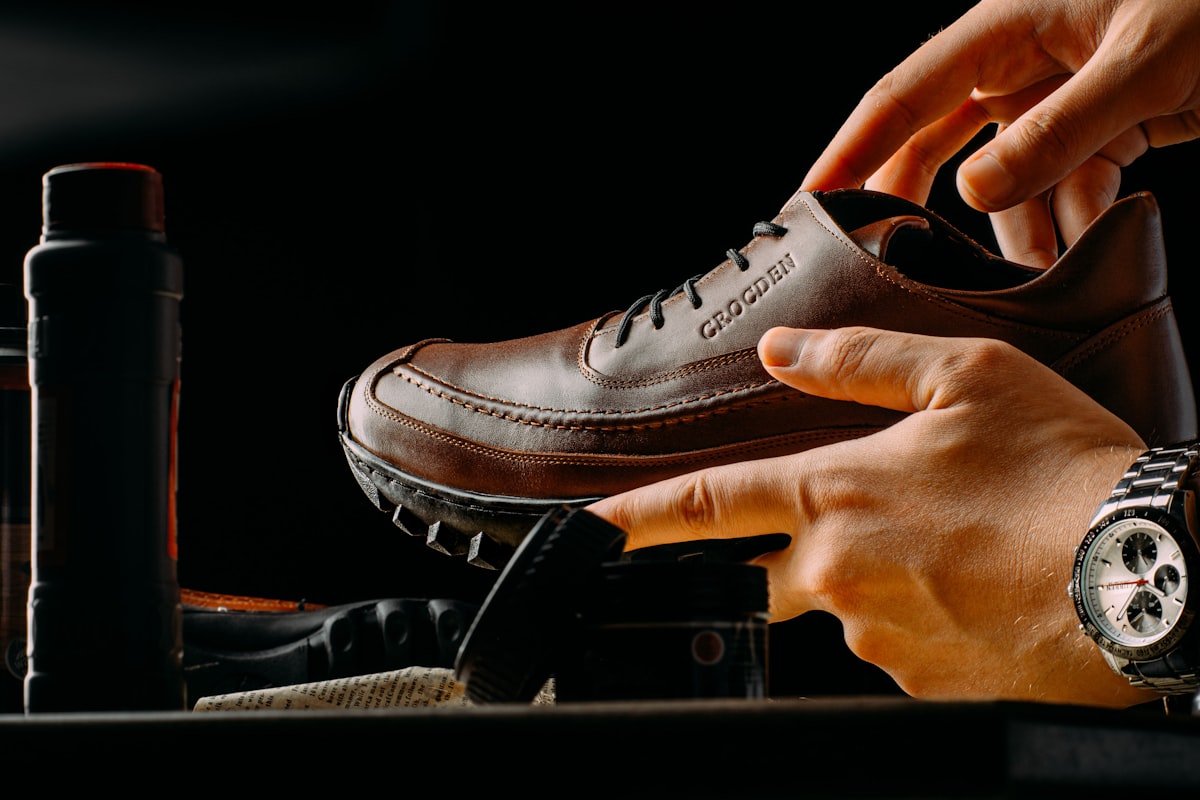 Hands finishing a premium brown leather shoe